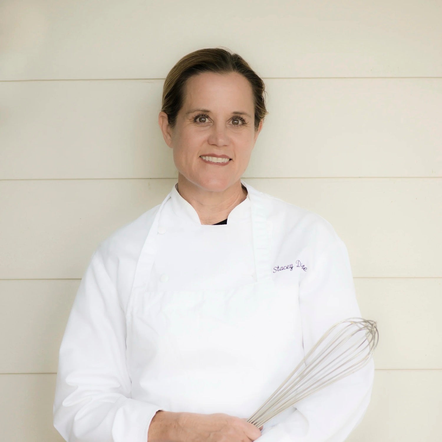 Chef Stacey in whites holding a whisk